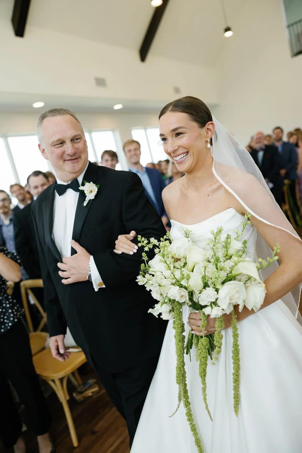 A bride walking down the aisle at River Road Venue, with her father