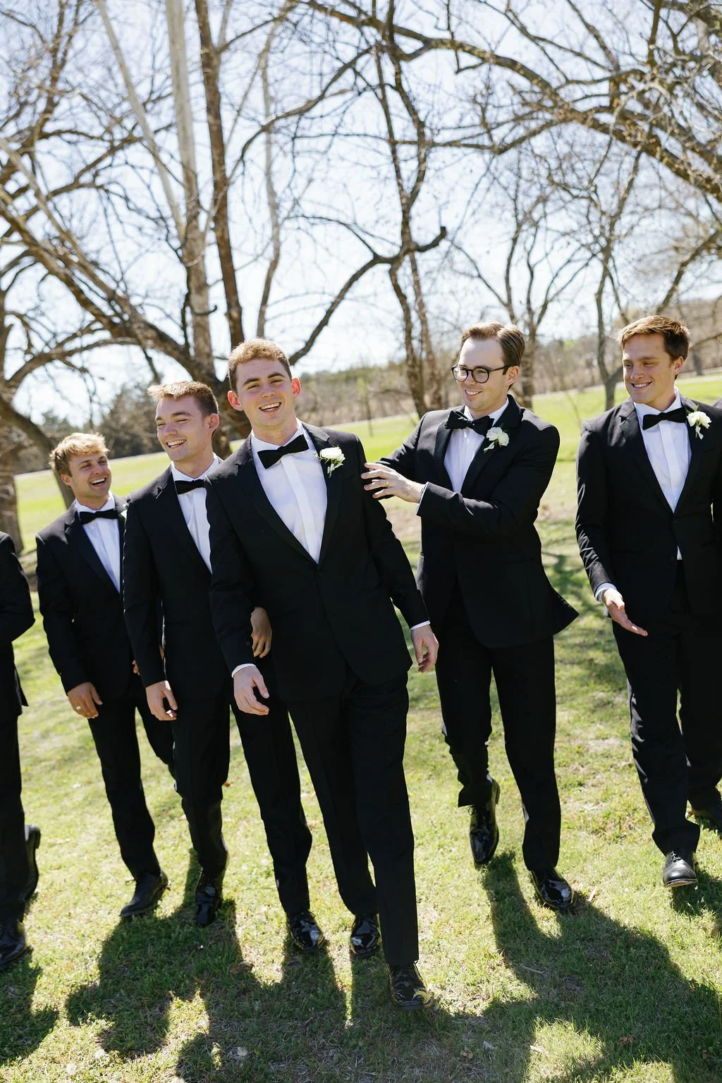 Groom and groomsmen portraits at River Road Venue, with the men in black tuxedos, and white boutonnieres 
