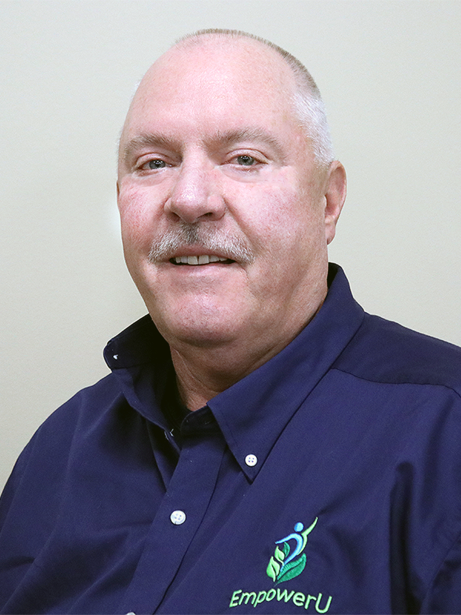 Man in blue shirt with "EmpowerU" logo posing for a portrait.