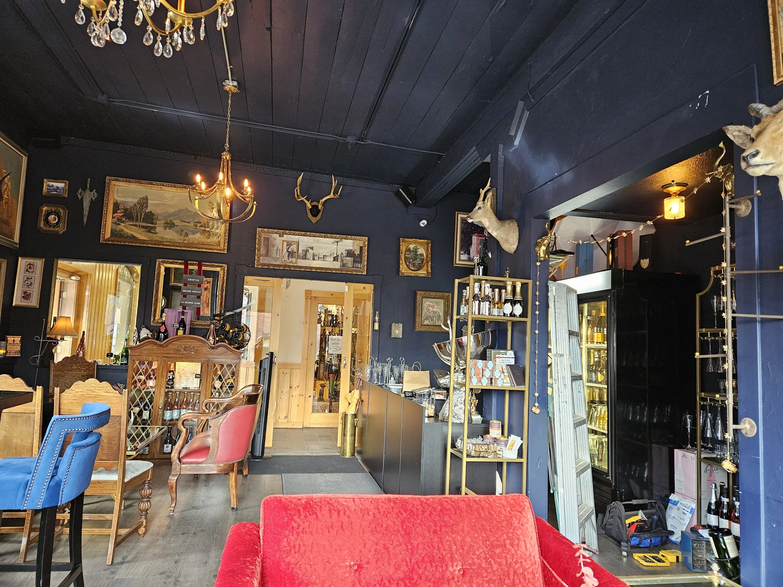 Interior of a Champagne bar decorated with paintings, animal heads mounted on the wall, a chandelier, and various luxurious furniture & decor items.