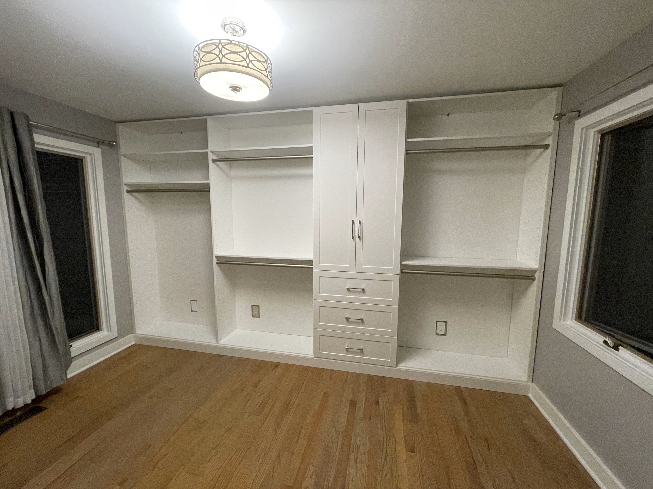 custom wardrobe with hanging space, cabinets, and built in dresser