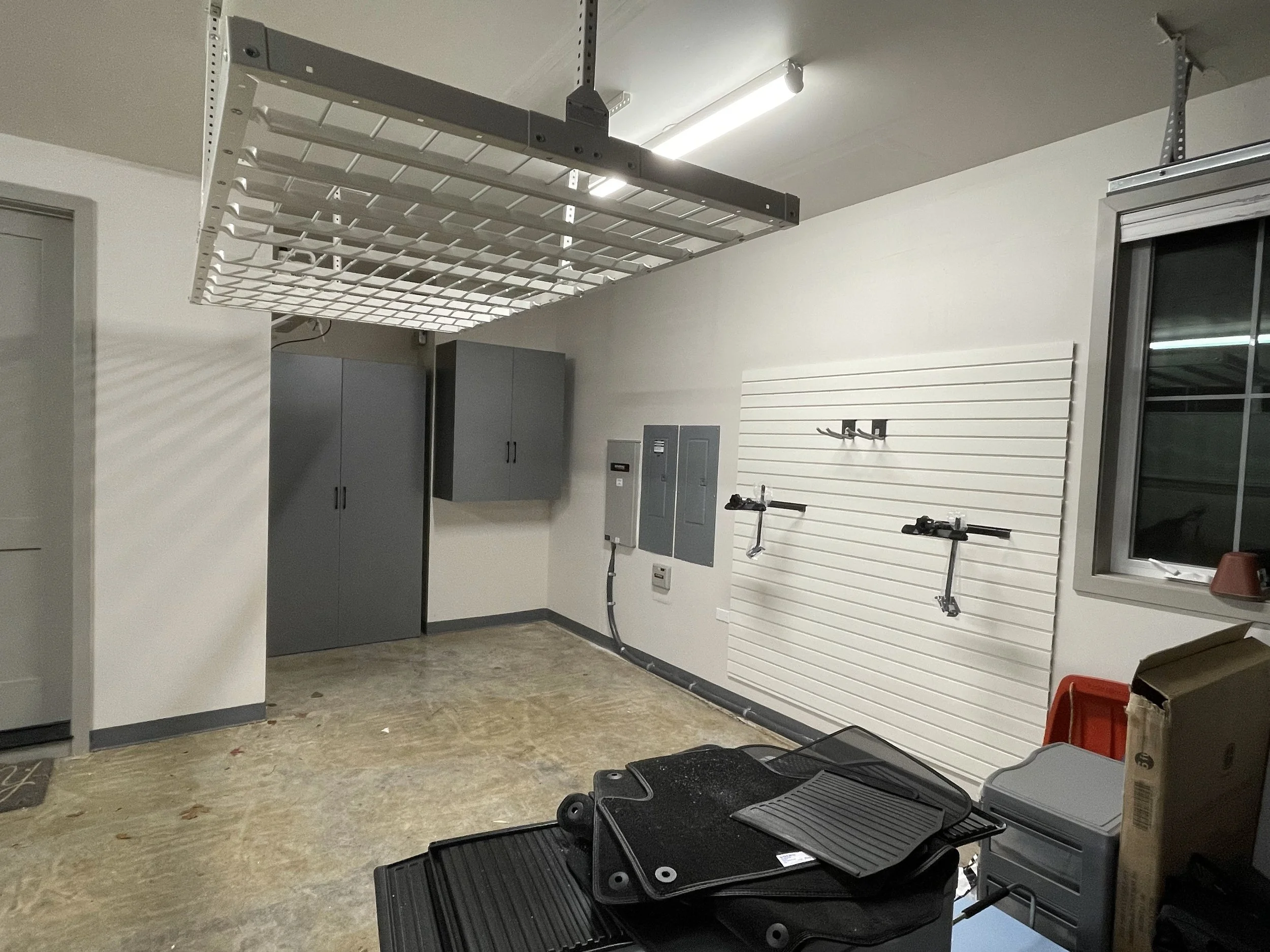 custom garage storage system with cabinets, overhead storage, and utility slat wall