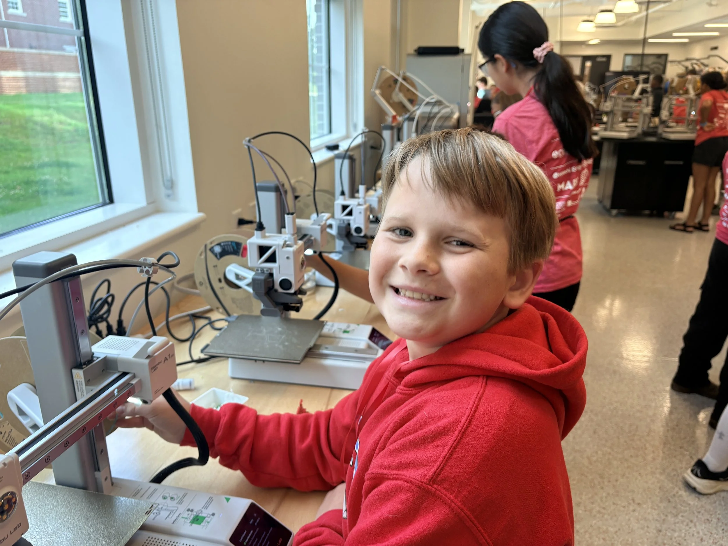 Boy smiling beside 3D printer