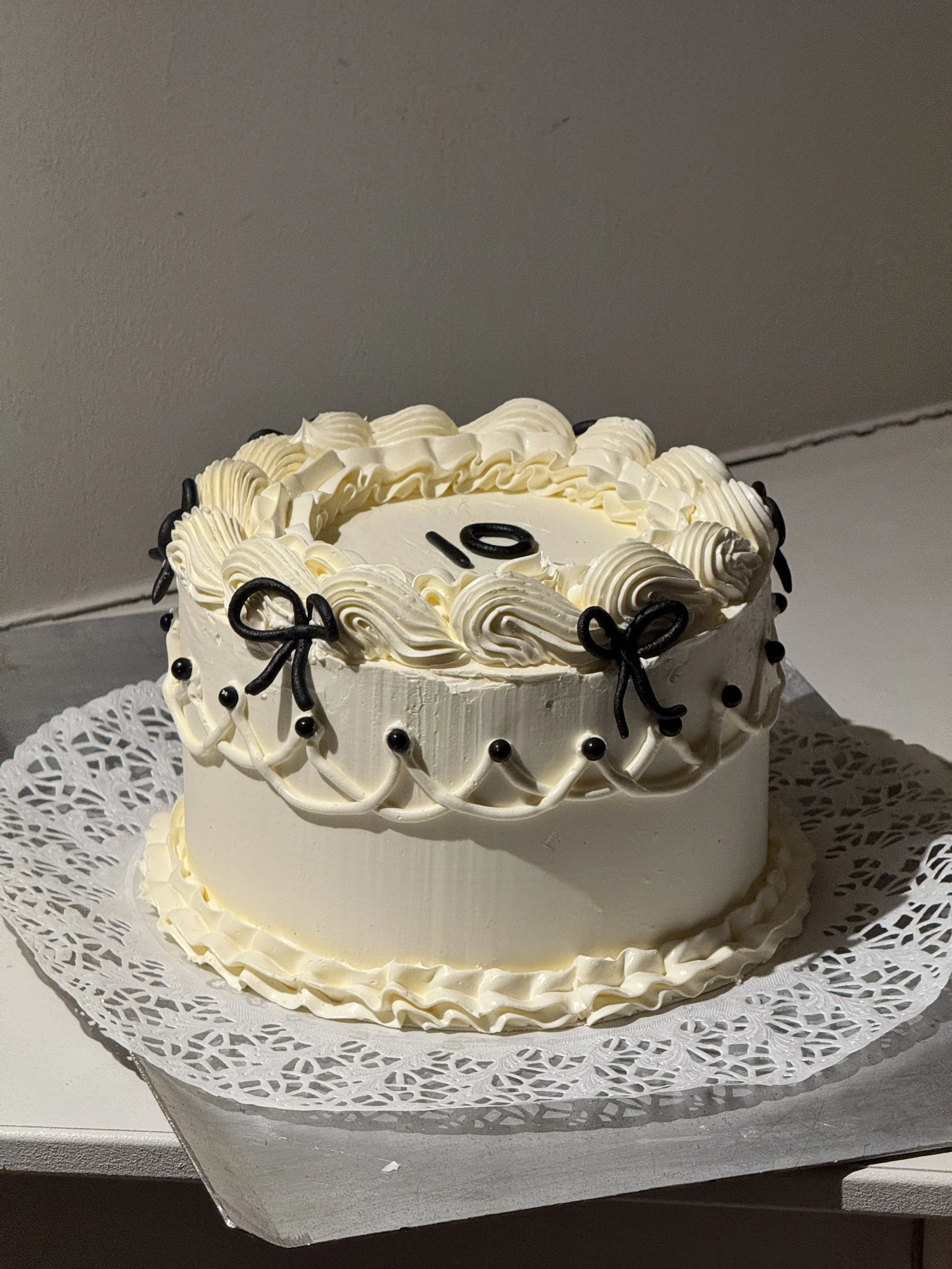 En trevåningstårta med blå och rosa blomdekorationer och rosa rosenblad runt botten.