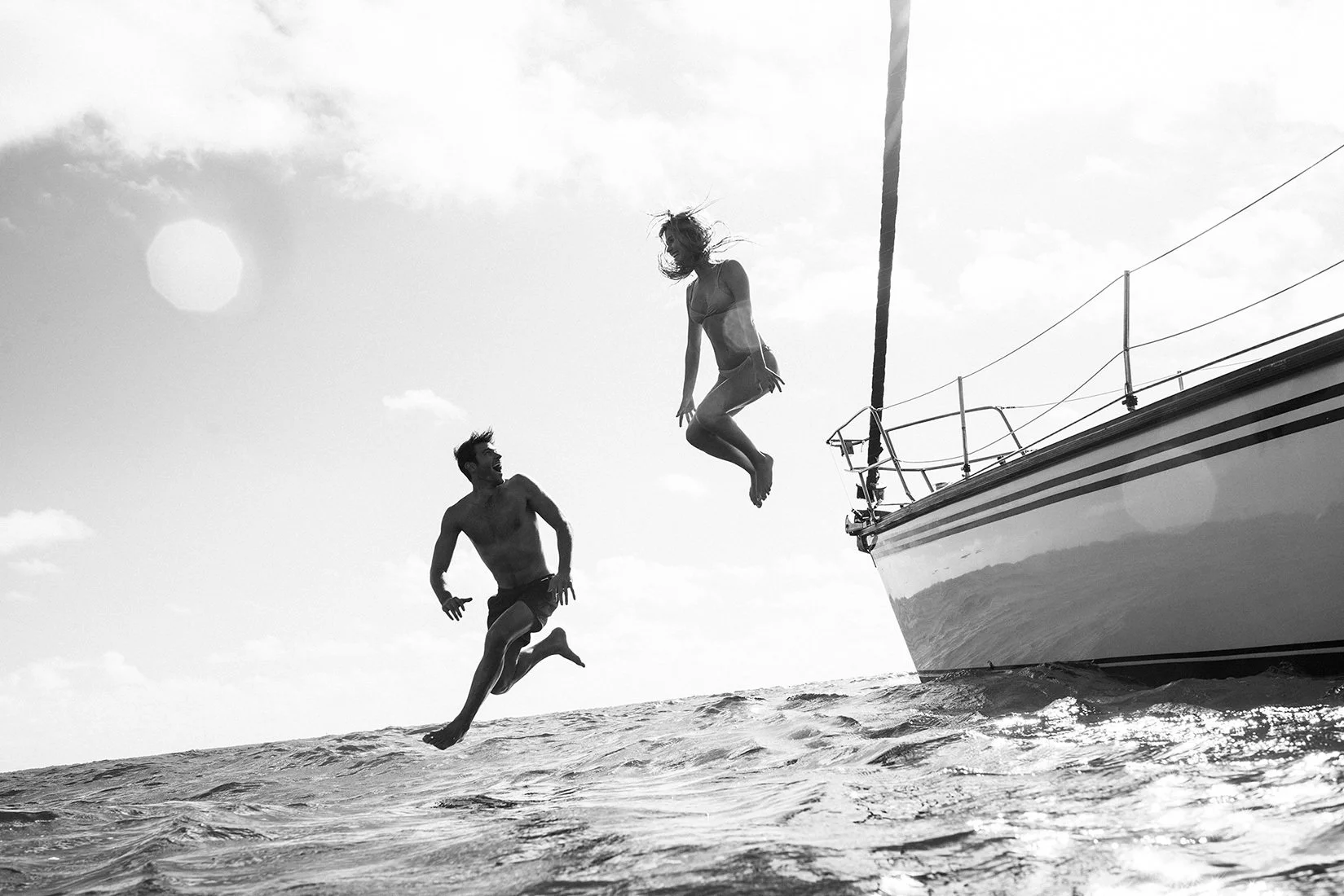 Two people jumping off a boat into the ocean