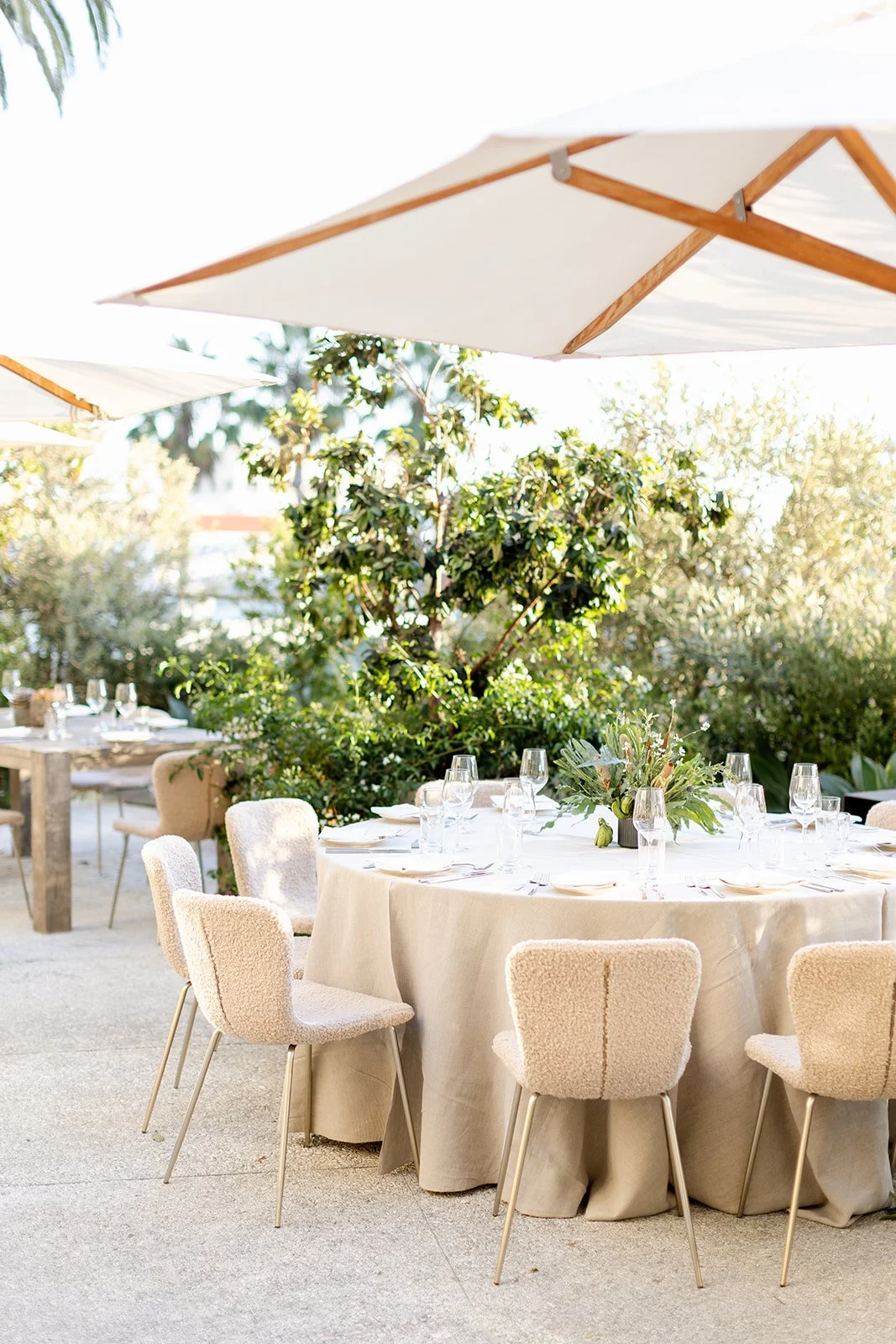 Elegant outdoor event table setting in Newport Beach, featuring a unique tropical floral centerpiece with greenery, small bananas, and native blooms. Perfect for luxury weddings, corporate dinners, and private parties. Captured by Tiffany Perry Photo