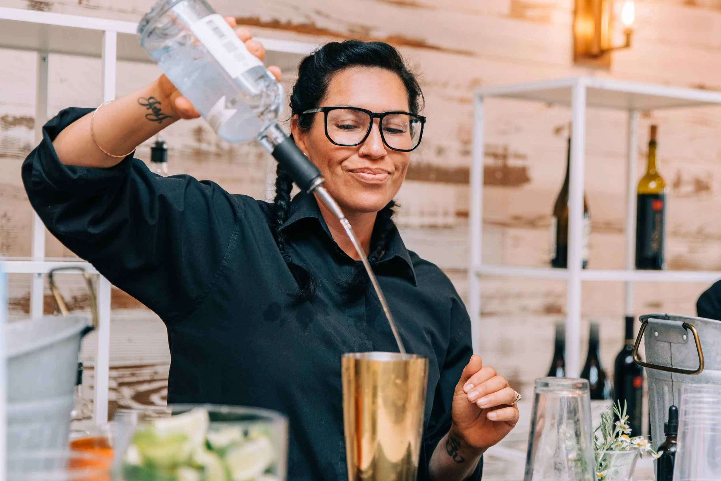 Expert bartender crafting cocktails at a Costa Mesa corporate event, pouring premium liquor into a shaker in a stylish modern bar setting, captured by Tiffany Perry Photography and Photo Booth Squared.
