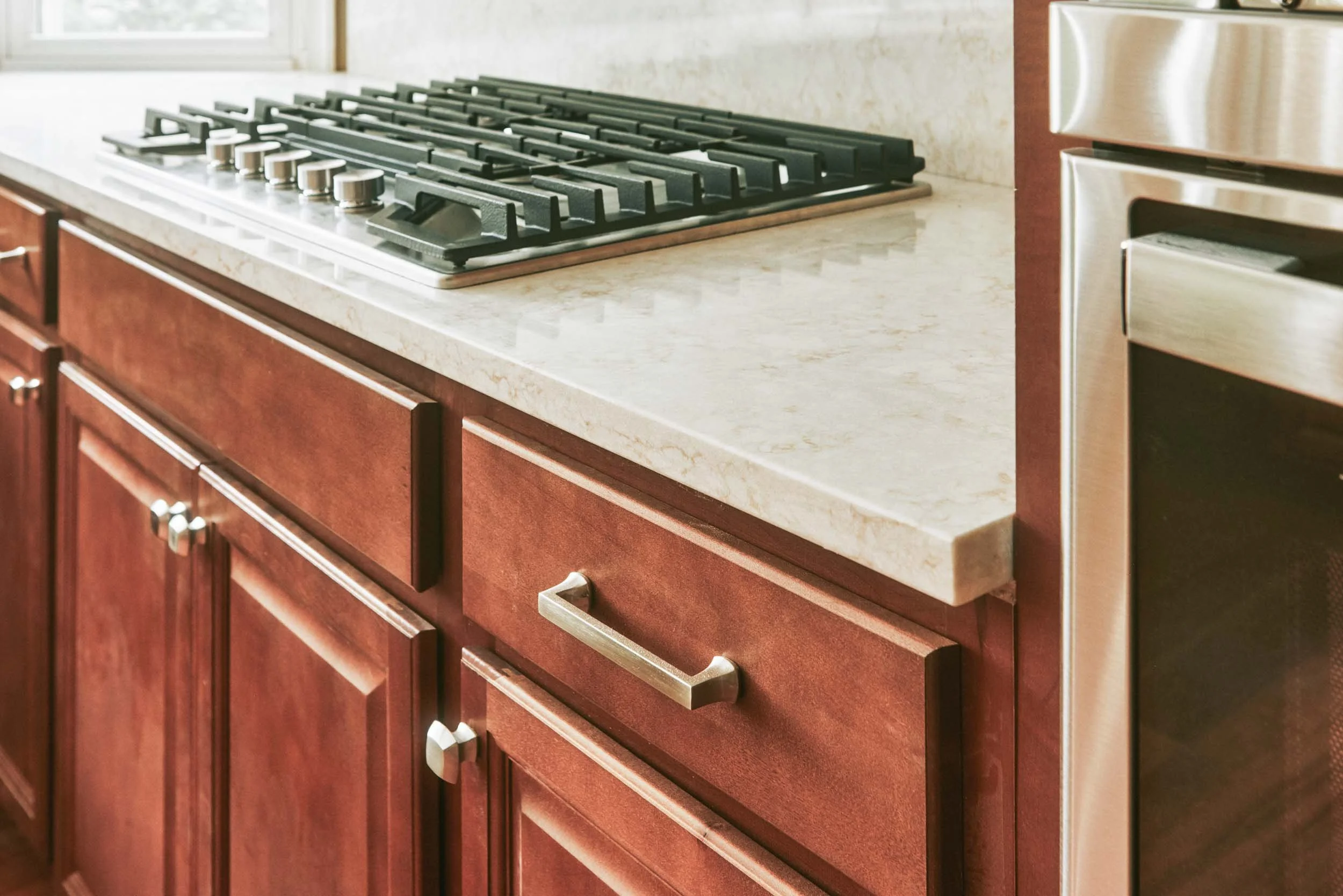 Close-up of kitchen countertop with a gas stove and wooden cabinets.
