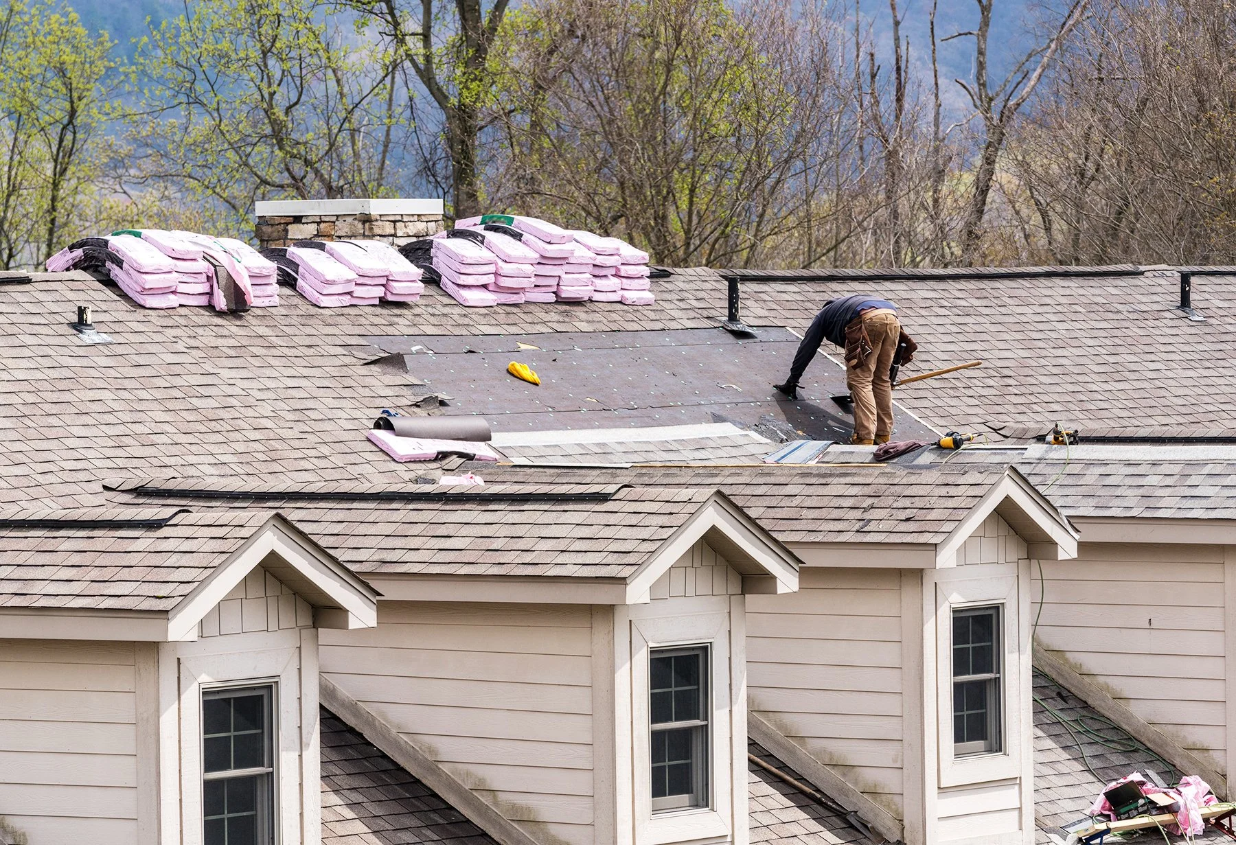 Roofer replacing roof shingles and adding insulation