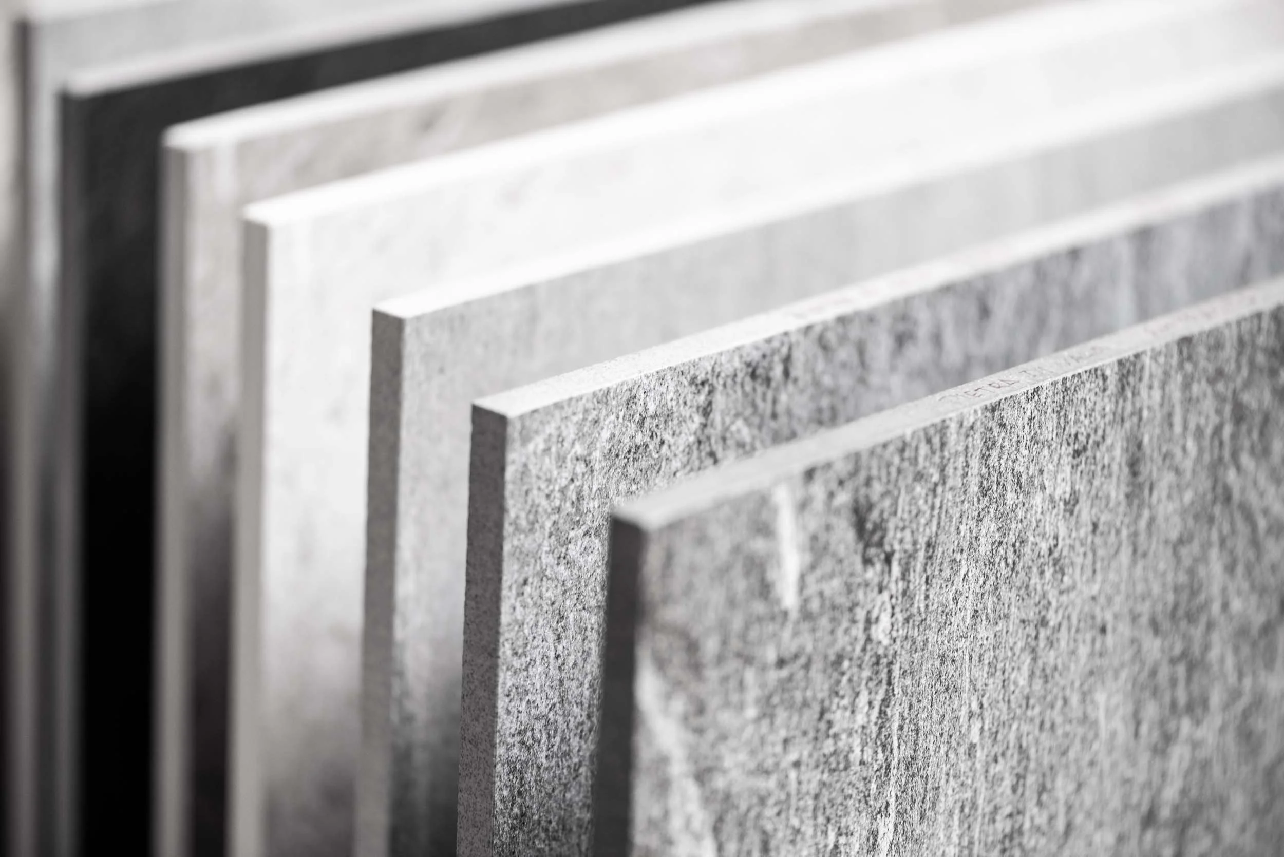 Close-up of several gray concrete or stone tiles or panels, arranged in a diagonal line.