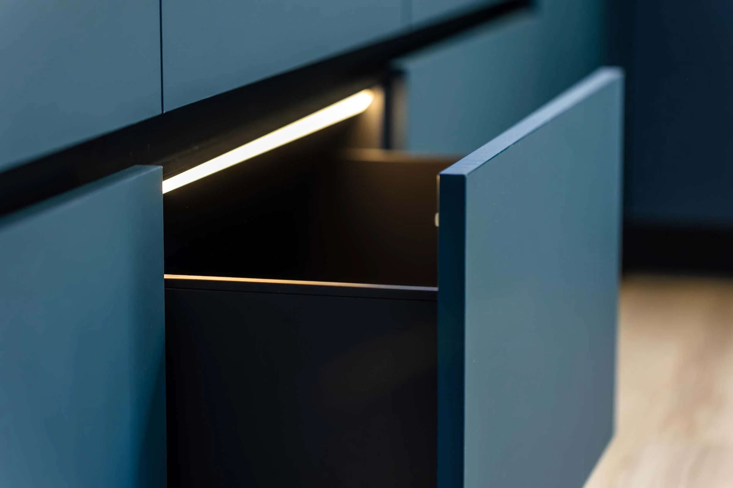 Open dark blue cabinet drawer with integrated lighting.