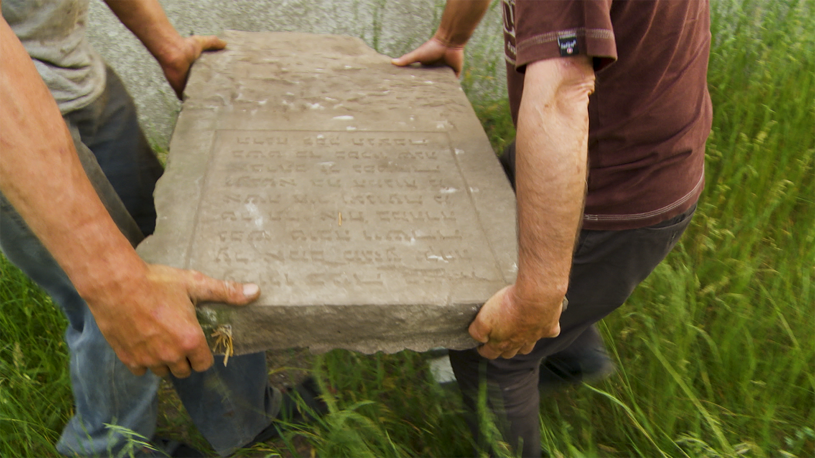 Two Polish men return a stolen Hebrew tombstone to the Jewish cemetery in the small town of Gniewoszów in the documentary film Among Neighbors directed by Yoav Potash.png
