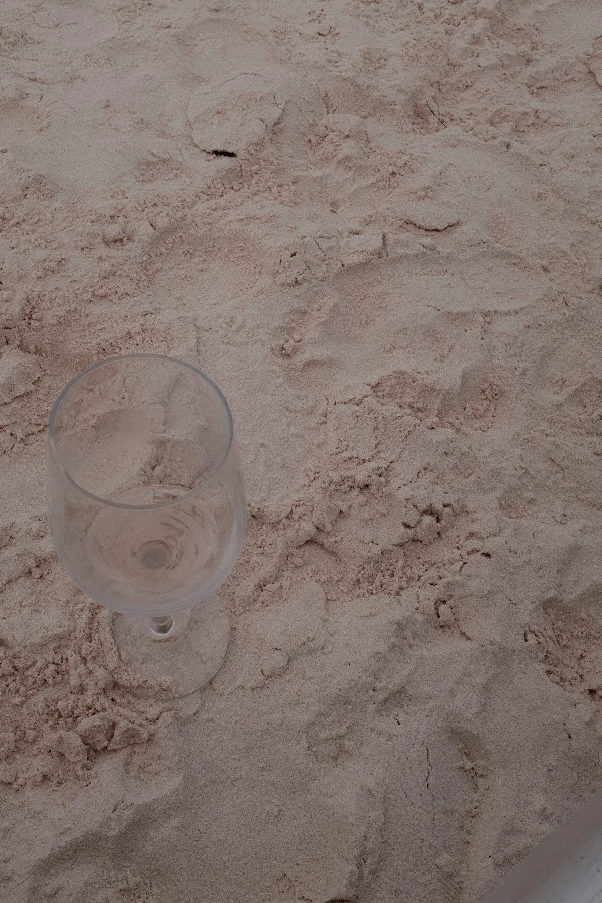 Empty wine glass on sandy beach