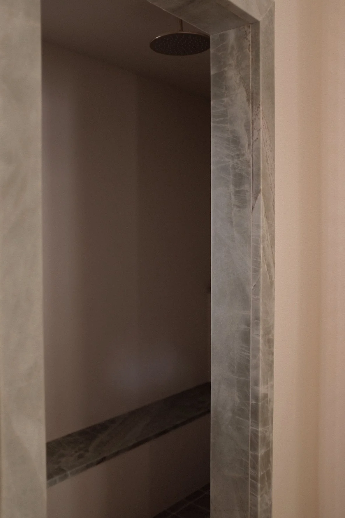 Empty shower with a rain showerhead and marble tile accents.