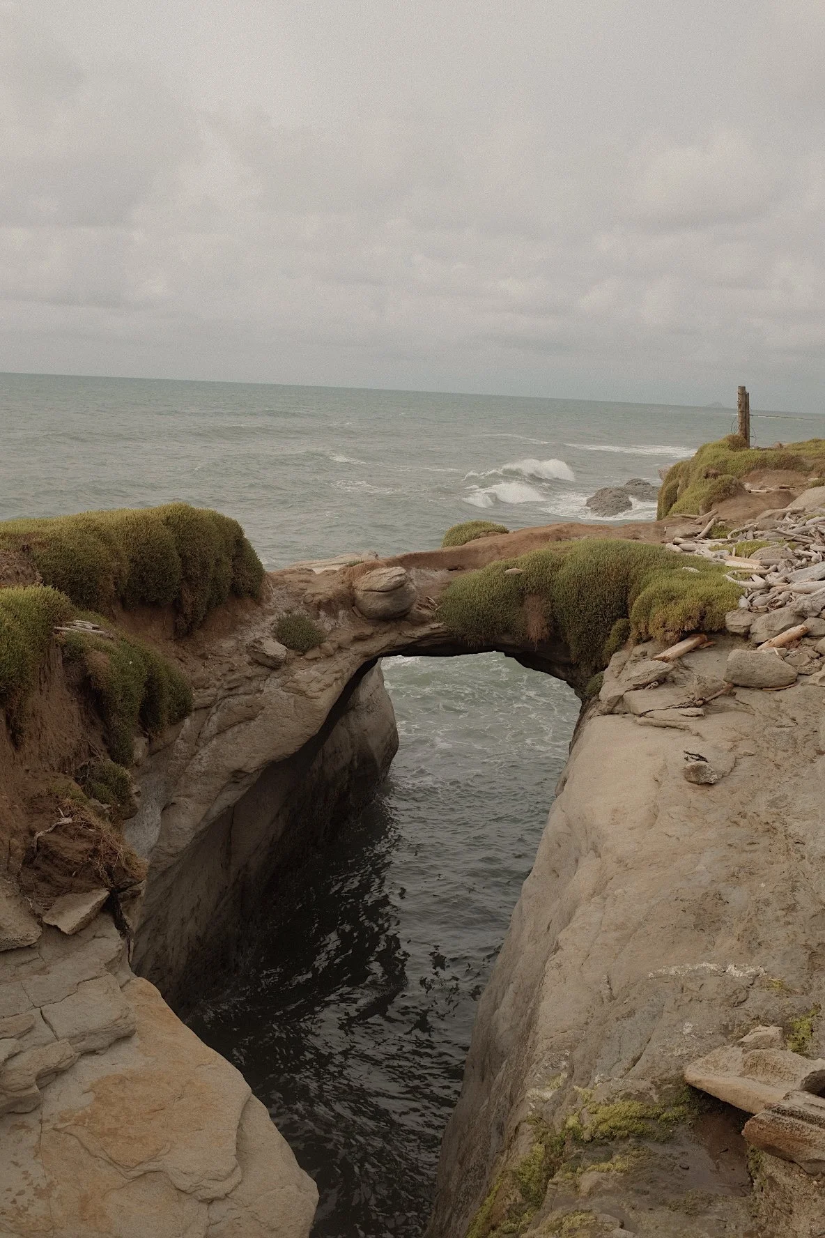 Rocky coast with natural stone arch and sea view.