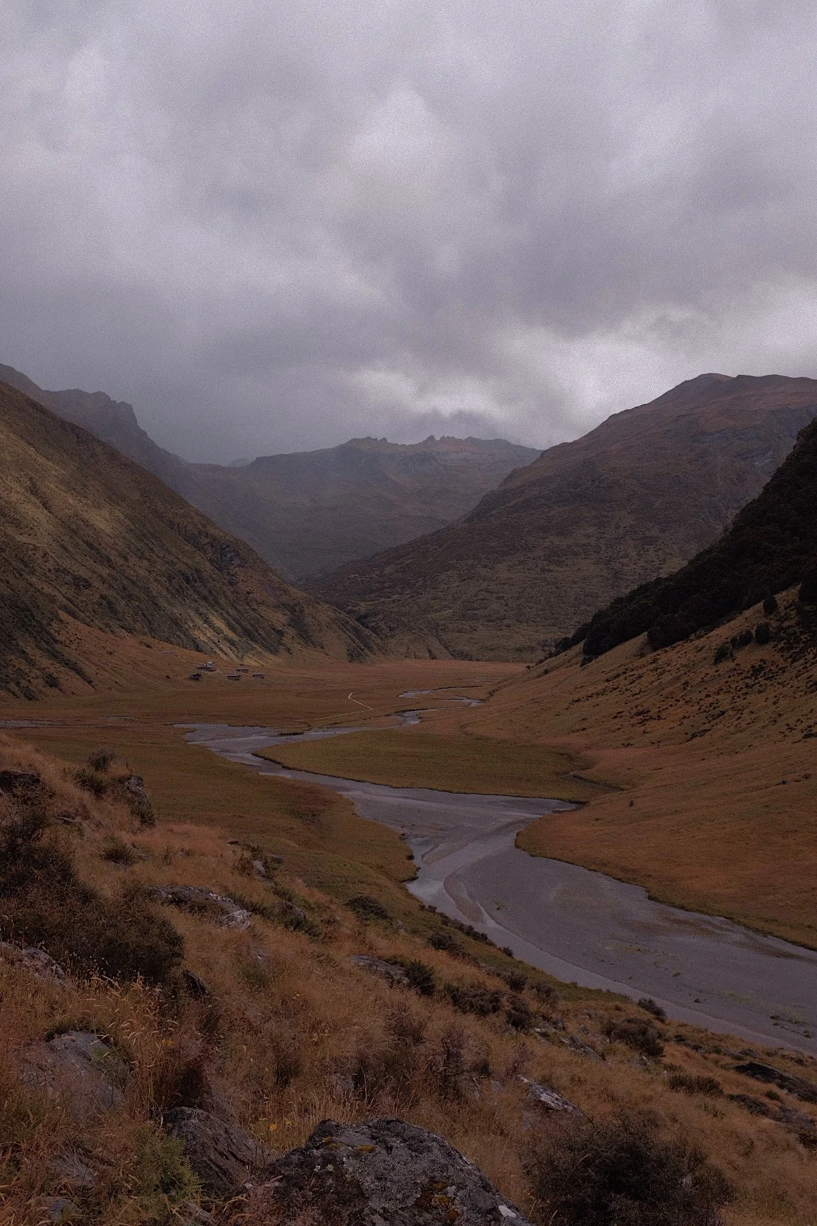 Mountain valley landscape with a winding river and overcast sky.