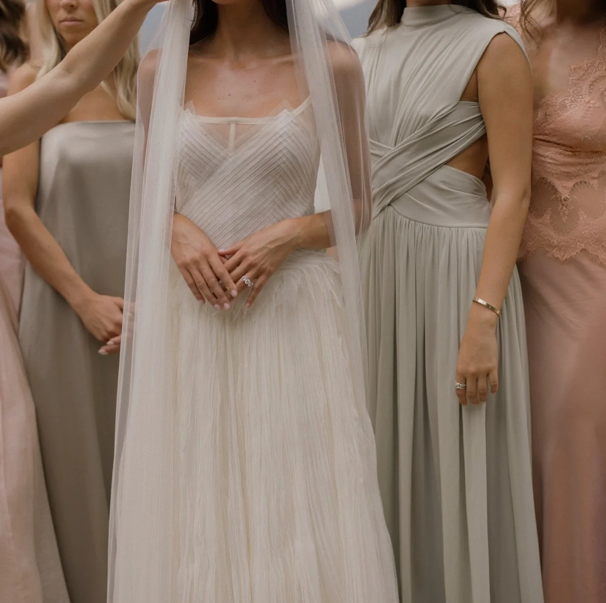 Bride in a white wedding dress with bridesmaids in elegant gowns, close-up.