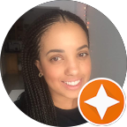 Close-up of a smiling woman with braids and earrings, in front of a dark background