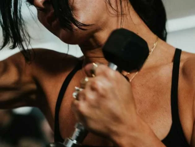 A woman lifting a dumbbell in a gym.