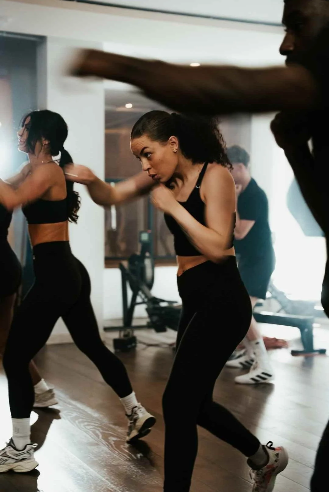 People participating in a fitness class, engaging in a punch combination, wearing athletic clothing in an indoor gym or studio.