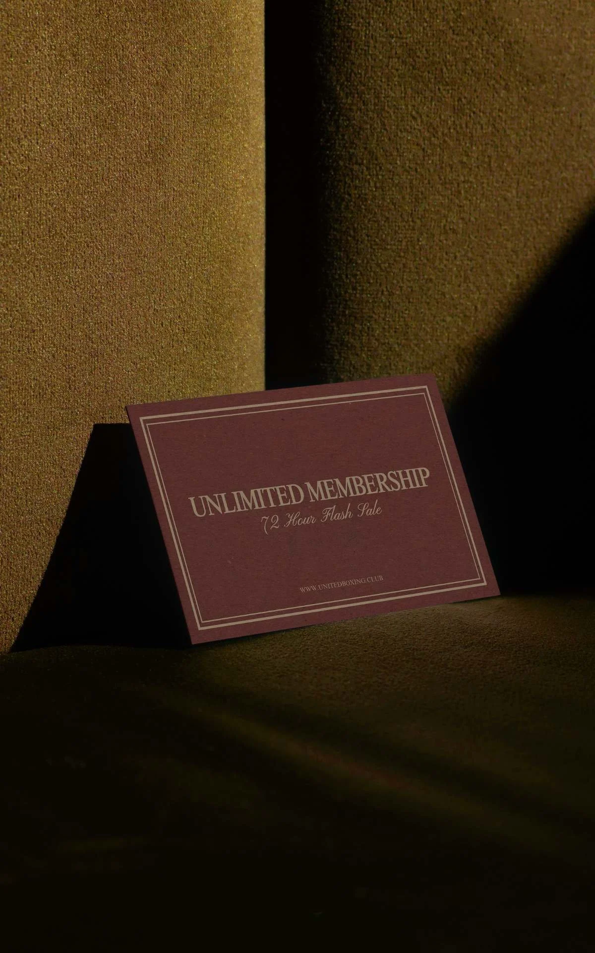 A maroon card with white borders that reads "Unlimited Membership 72 Hour Flash Sale" and a website URL at the bottom, placed on a textured, dark-colored surface with shadows.