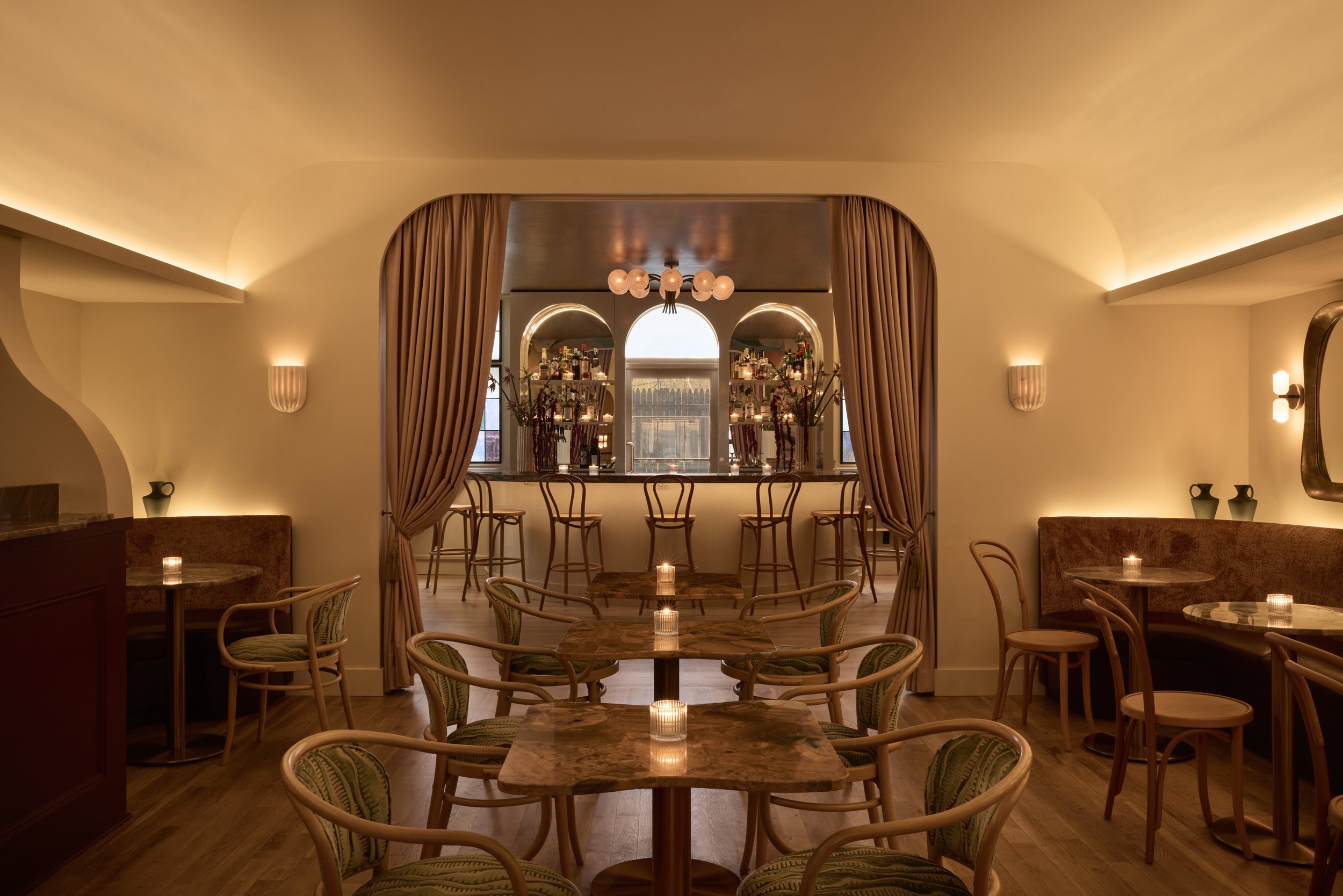 Shy Shy's private event space in Chelsea, NYC, featuring warm ambient lighting, elegant seating, and a stylish bar framed with rich velvet curtains. Ideal for birthdays, corporate events, and intimate gatherings in Manhattan