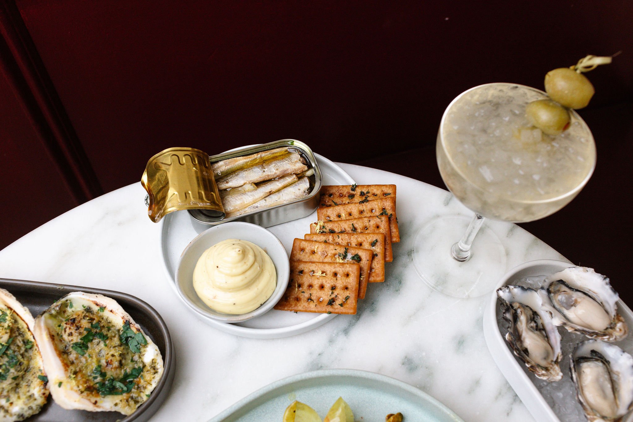 Tinned seafood and a dirty martini at Shy Shy in Chelsea, NYC, featuring premium sardines, house-made aioli, crispy crackers. A perfect pairing for an elevated cocktail experience.