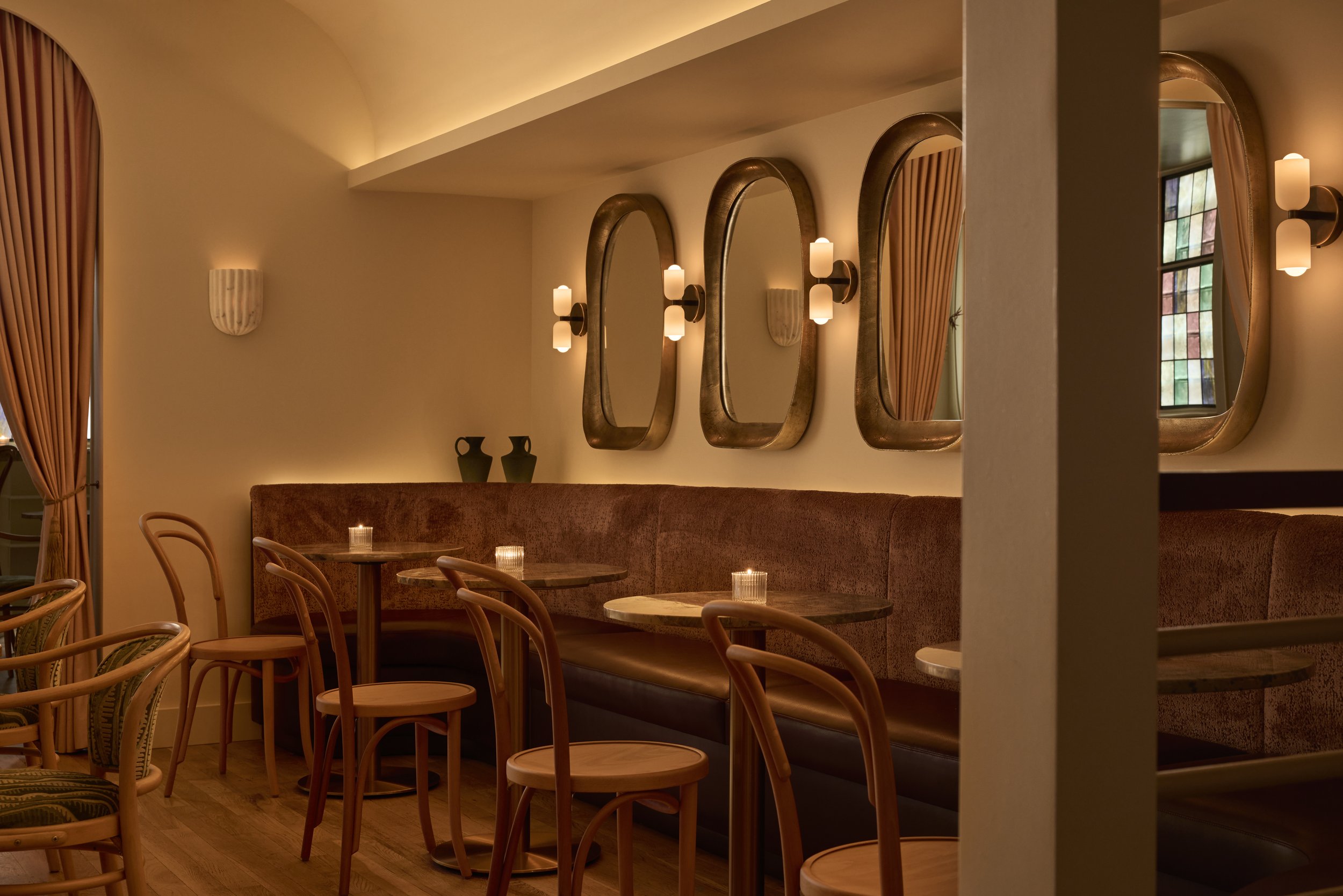 Shy Shy's intimate cocktail lounge and dining area in Chelsea, NYC, featuring plush banquette seating, warm lighting, and vintage-inspired mirrors. A perfect setting for craft cocktails, martinis, private gatherings and upscale dining.