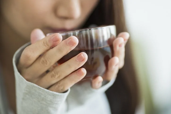 A person gently holds and drinks from a warm cup.