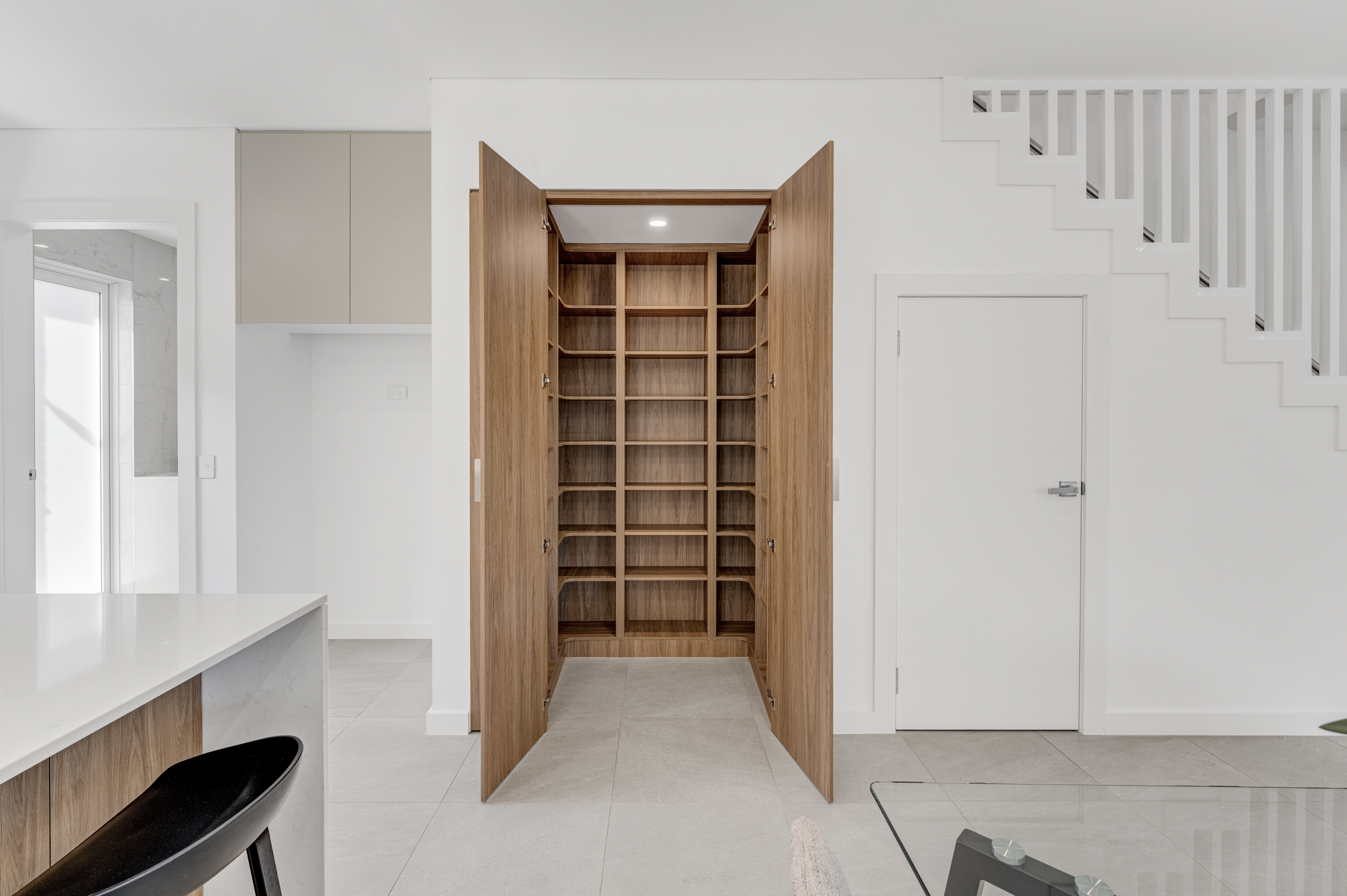 Empty wooden open cabinet with multiple shelves in a modern white interior room.