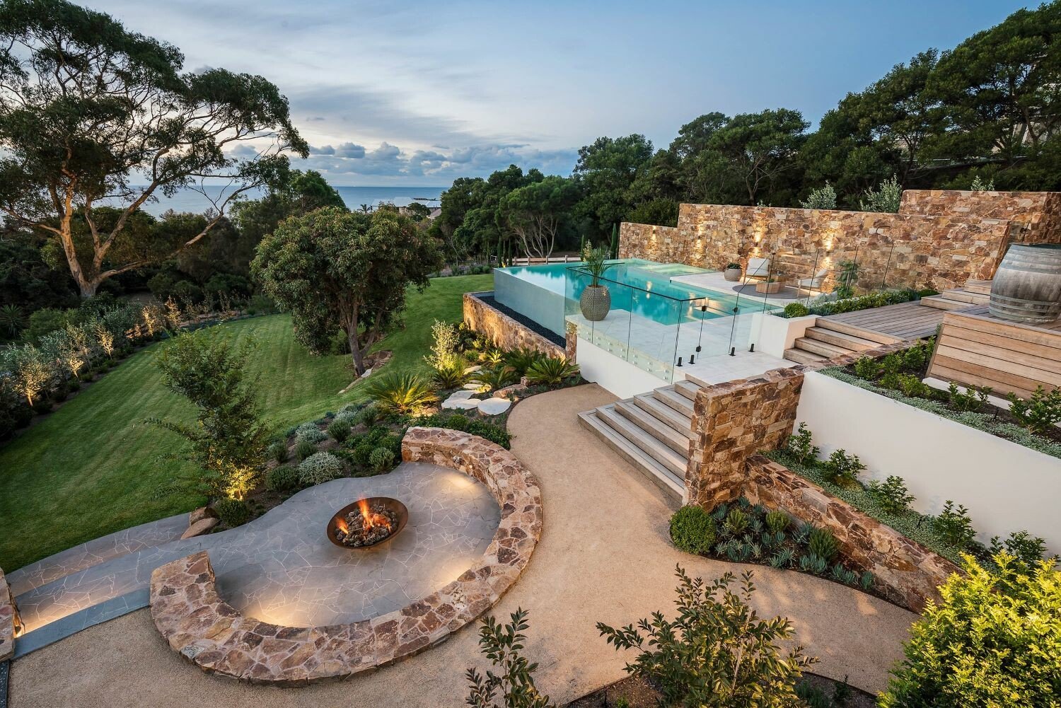 Custom luxury landscape design featuring fire pit area and pool