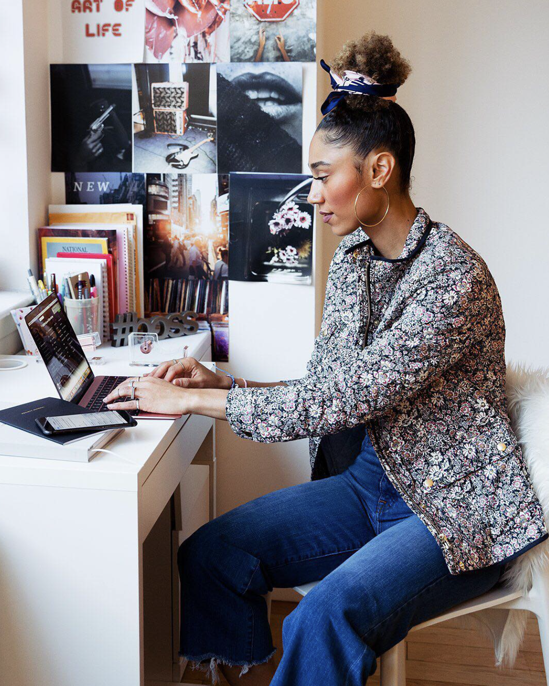 Woman working on a laptop at a desk in a decorated room