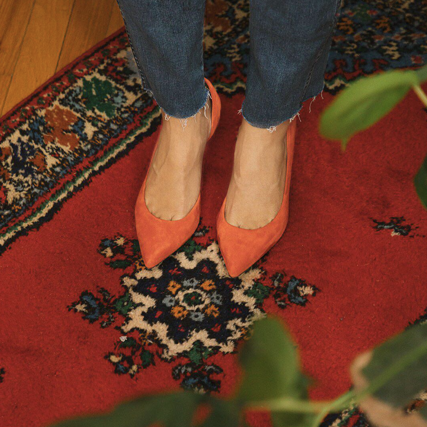 Person wearing orange shoes standing on a red patterned rug.