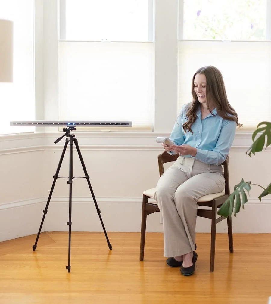 Michele Root, LCSW smiles as she is looking down, operating an EMDR bilateral stimulation device in a bright room.