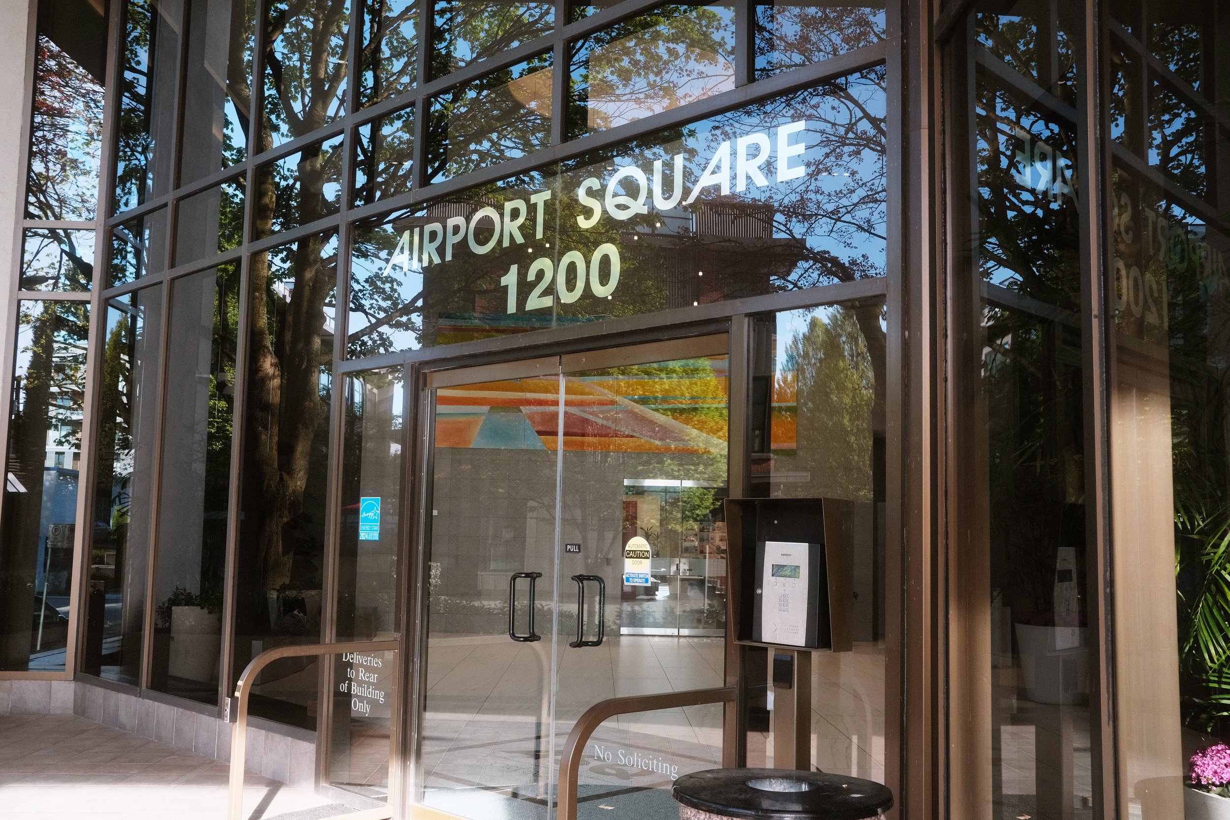 Entrance of Airport Square building with glass doors and "Airport Square 1200" sign above.