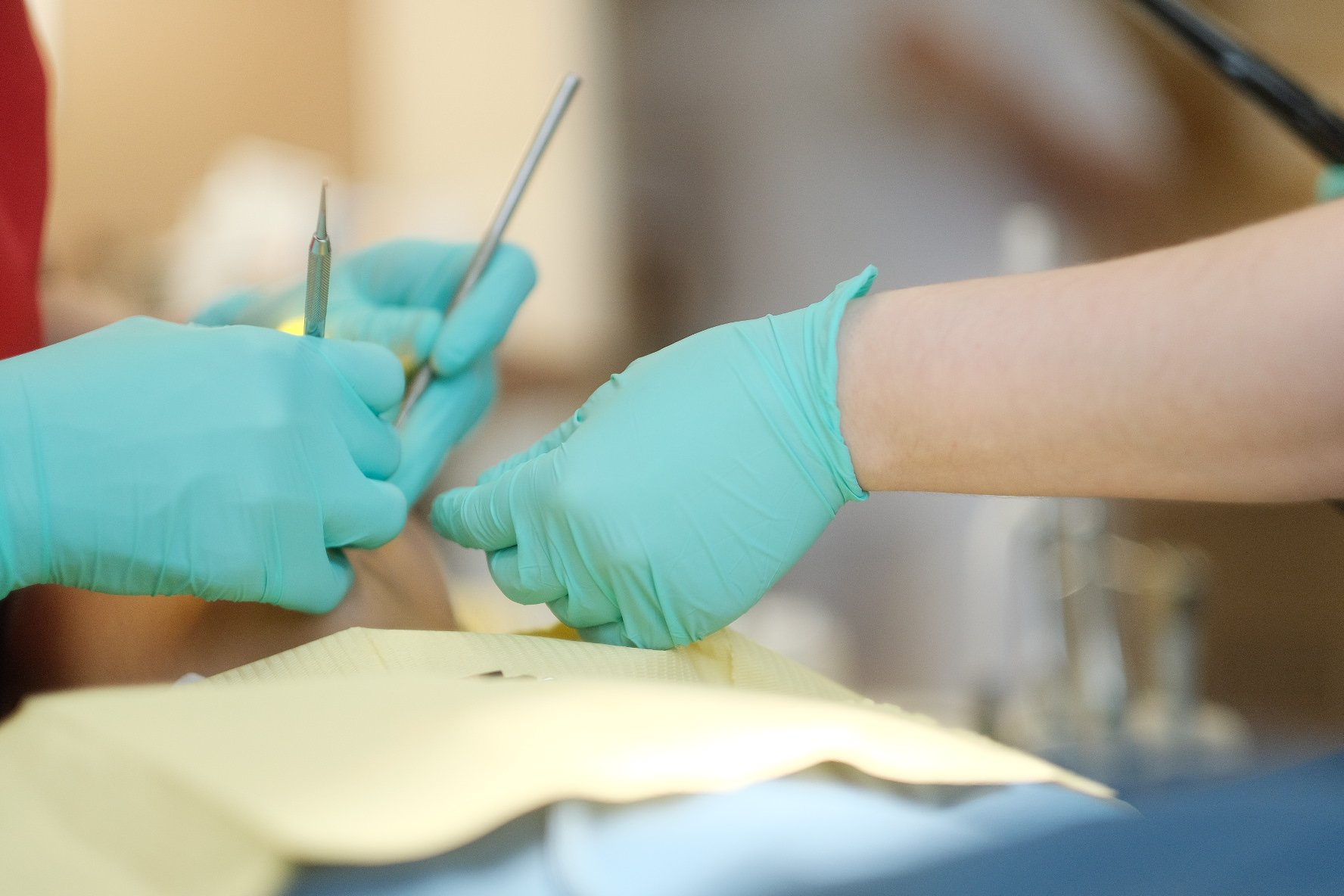 Hands in gloves performing a medical procedure with tools.