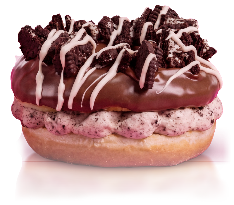 Close-up of a gourmet donut with chocolate glaze, topped with crushed cookies, white icing drizzle, and colorful sprinkles.