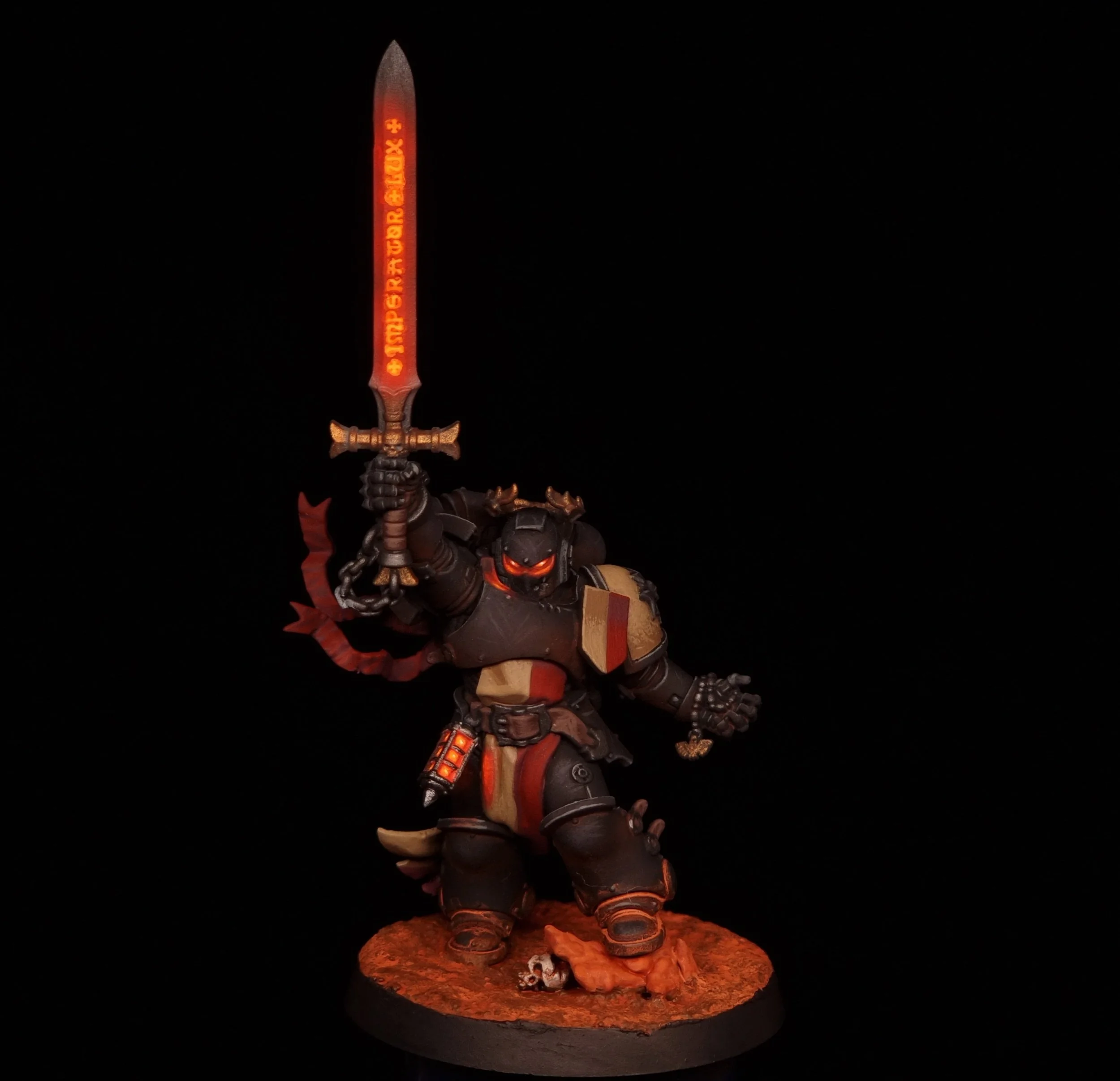 A detailed miniature figurine of a sci-fi robotic warrior holding a glowing red sword, standing on a textured orange base with skull decorations, against a black background.