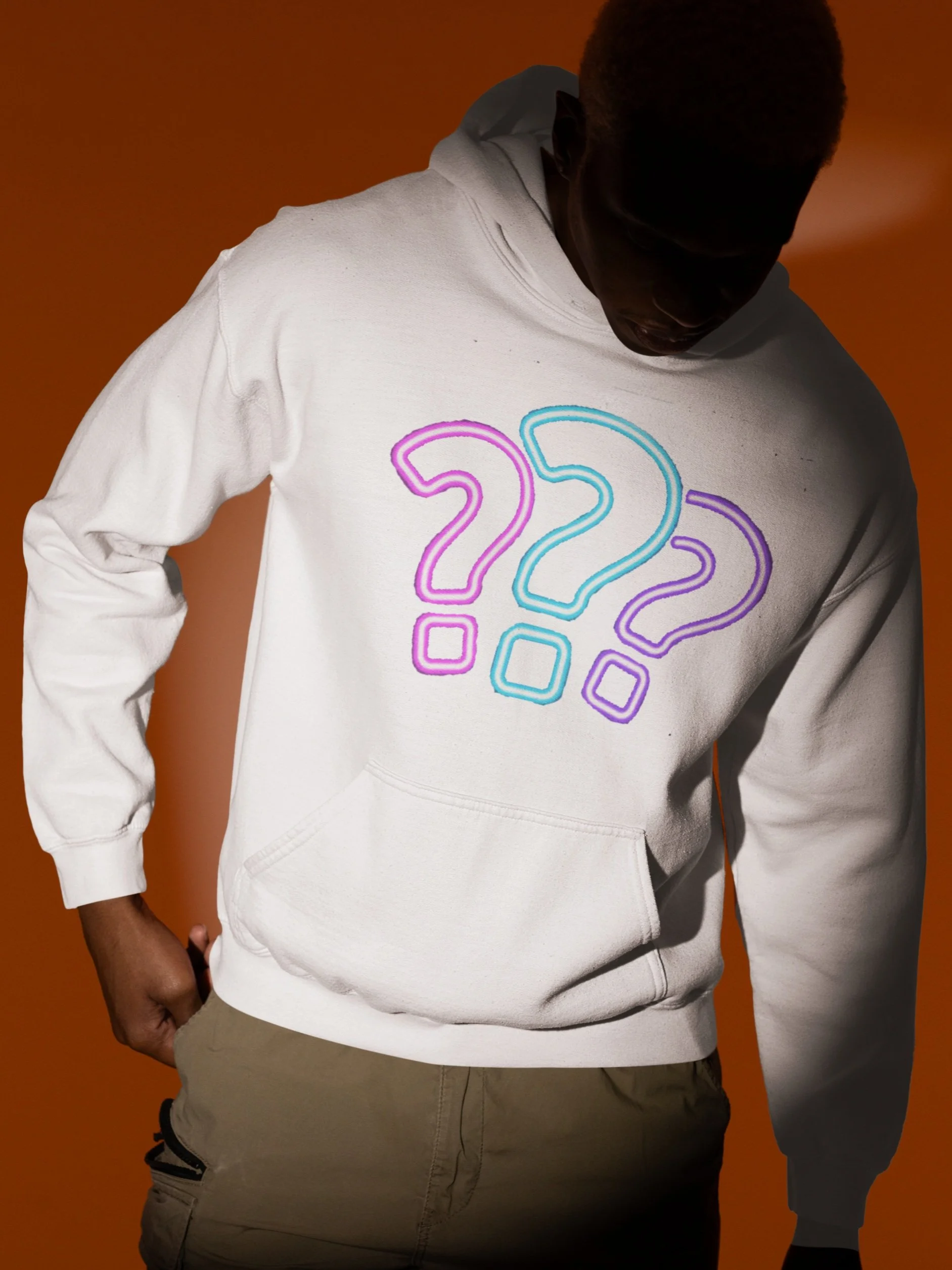 A person wearing a white hoodie with multicolored question marks on the front, standing against an orange background.