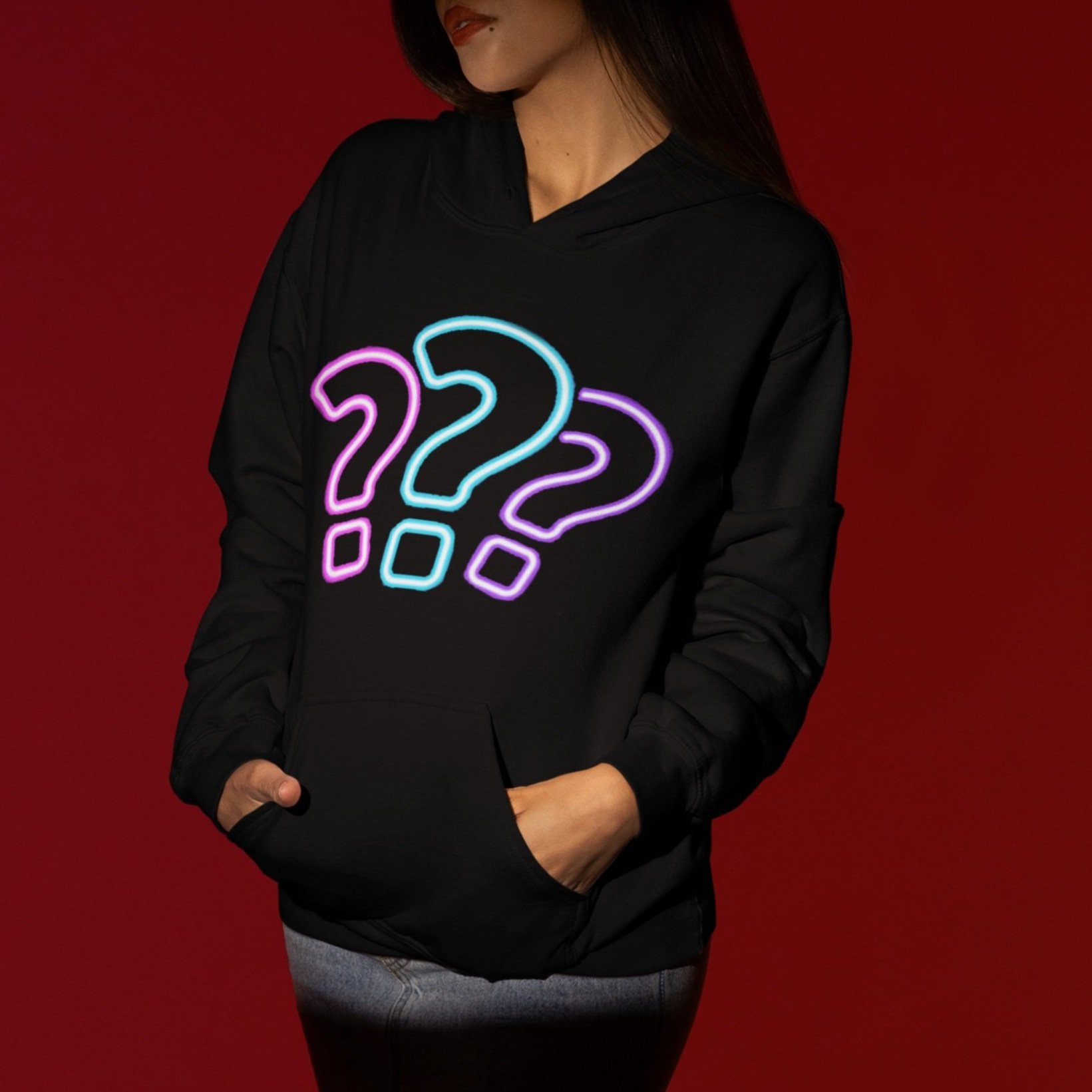 A woman wearing a black hoodie with illuminated neon-style question mark symbols on the front against a red gradient background.