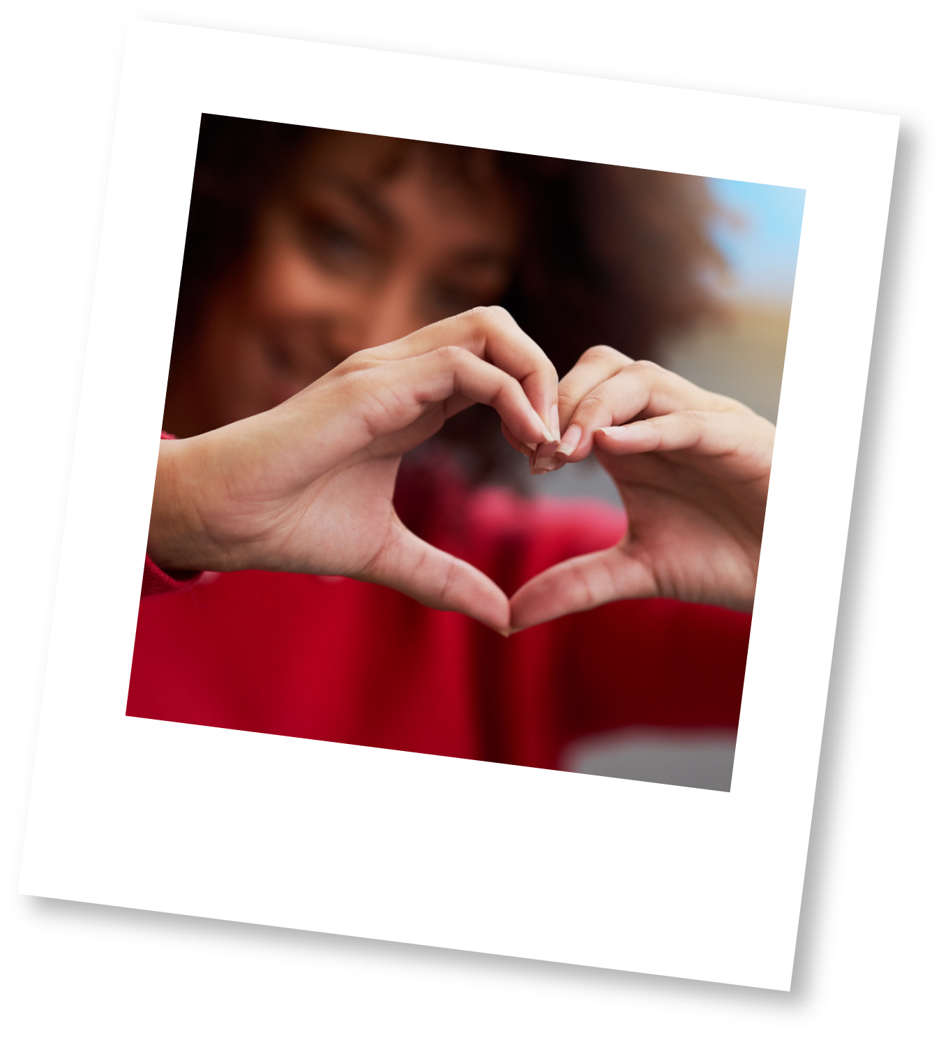 Person with curly red hair making a heart shape with their hands.