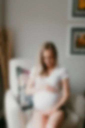 Pregnant woman sitting on a white chair.