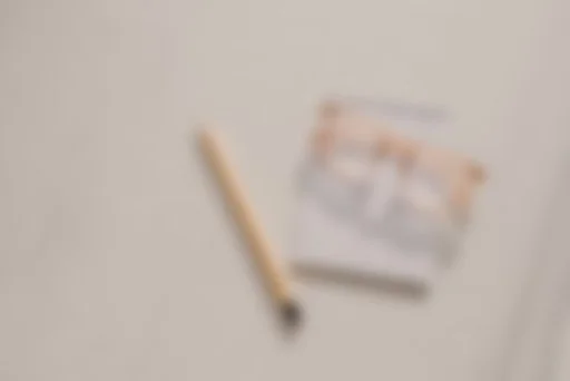 Blurry image of a pen and an open notebook on a table.