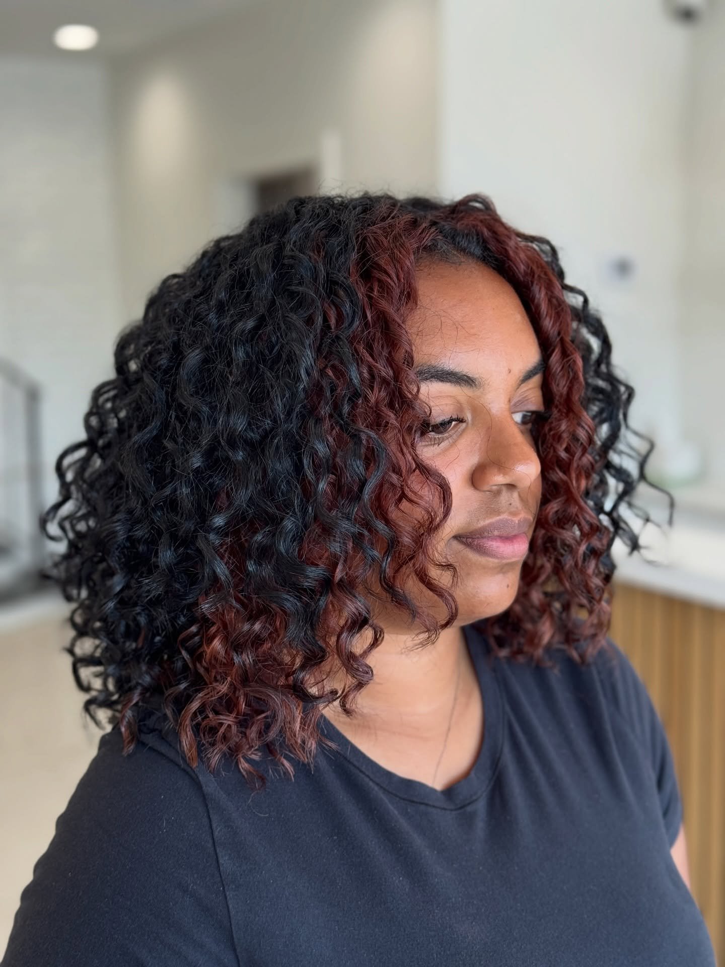 A little curly cut + a very intentional color refresh not a redo 
 We re-lightened the regrowth only in her halo section to maintain the original color-blocking placement, then re-toned that halo red to bring the warmth and richness back to life.
 To