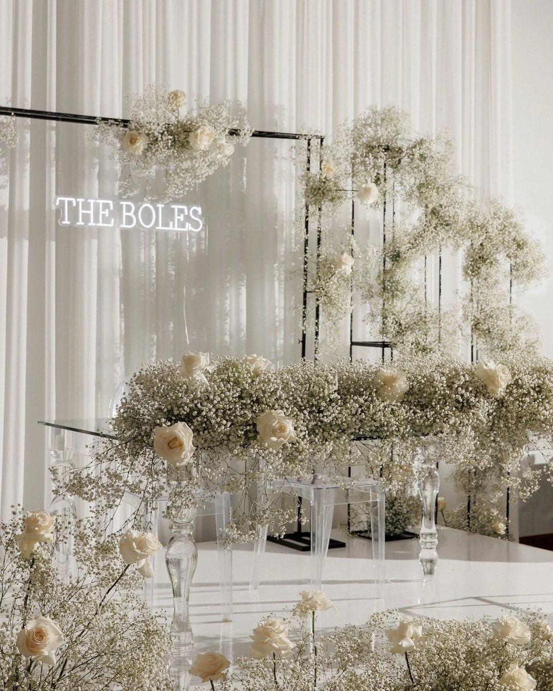 A dreamy ceremony setup with clouds of baby&rsquo;s breath and soft ivory roses, framed by sleek black stands and a custom neon sign. Minimalist, modern, and absolutely magical.
⠀⠀
⠀
#BabysBreathBackdrop #ModernWeddingDecor #WeddingCeremonyIdeas #Whi