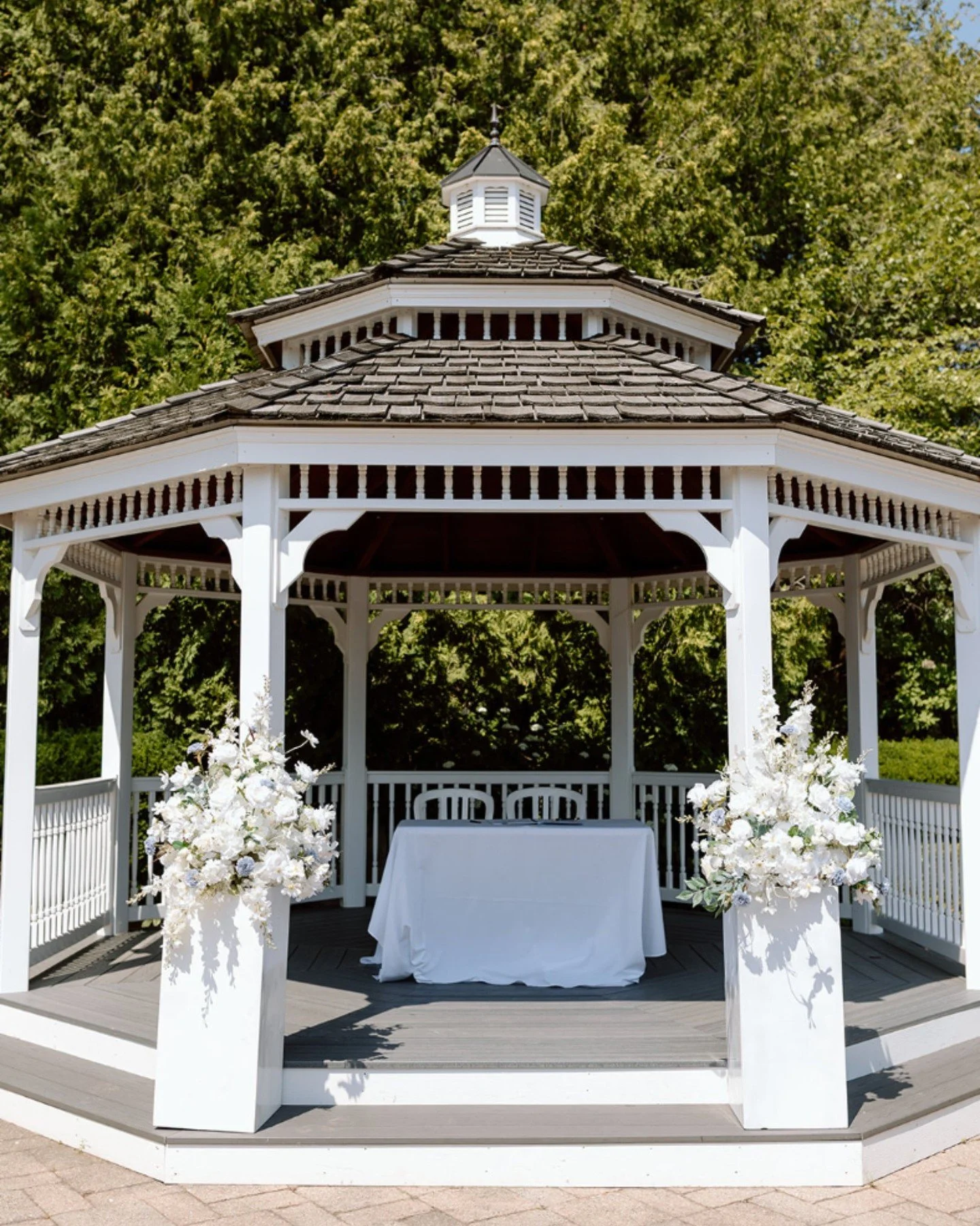 Elegant outdoor wedding ceremony setup under a classic white gazebo 🌿✨ Our white floral arrangements in lomey plate with lush roses, hydrangeas, and seasonal blooms added a soft romantic touch to this garden wedding. Perfect for saying &lsquo;I Do&r