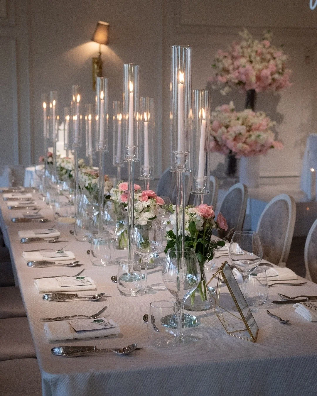 The bridal party table with tall crystal candle sticks. 

#torontoflorist #weddingsintoronto #weddingtrends2025 #blushandwhitewedding #weddinginspo #weddingflorist #freshflowers #weddingcenterpieces #wedding #weddingflowers #weddingfloraldeco #weddin
