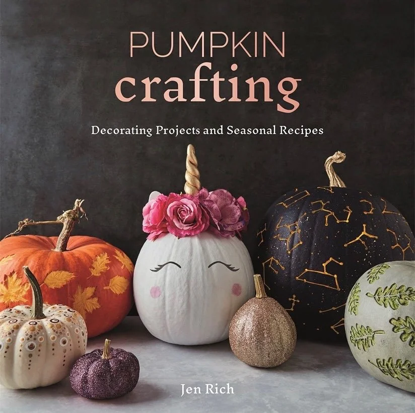 Cover of a book titled 'Pumpkin Crafting' featuring decorated pumpkins of various sizes and colors, including white, black with gold constellation designs, orange with leaves, and glittery gold and purple pumpkins, arranged on a surface against a dark background.