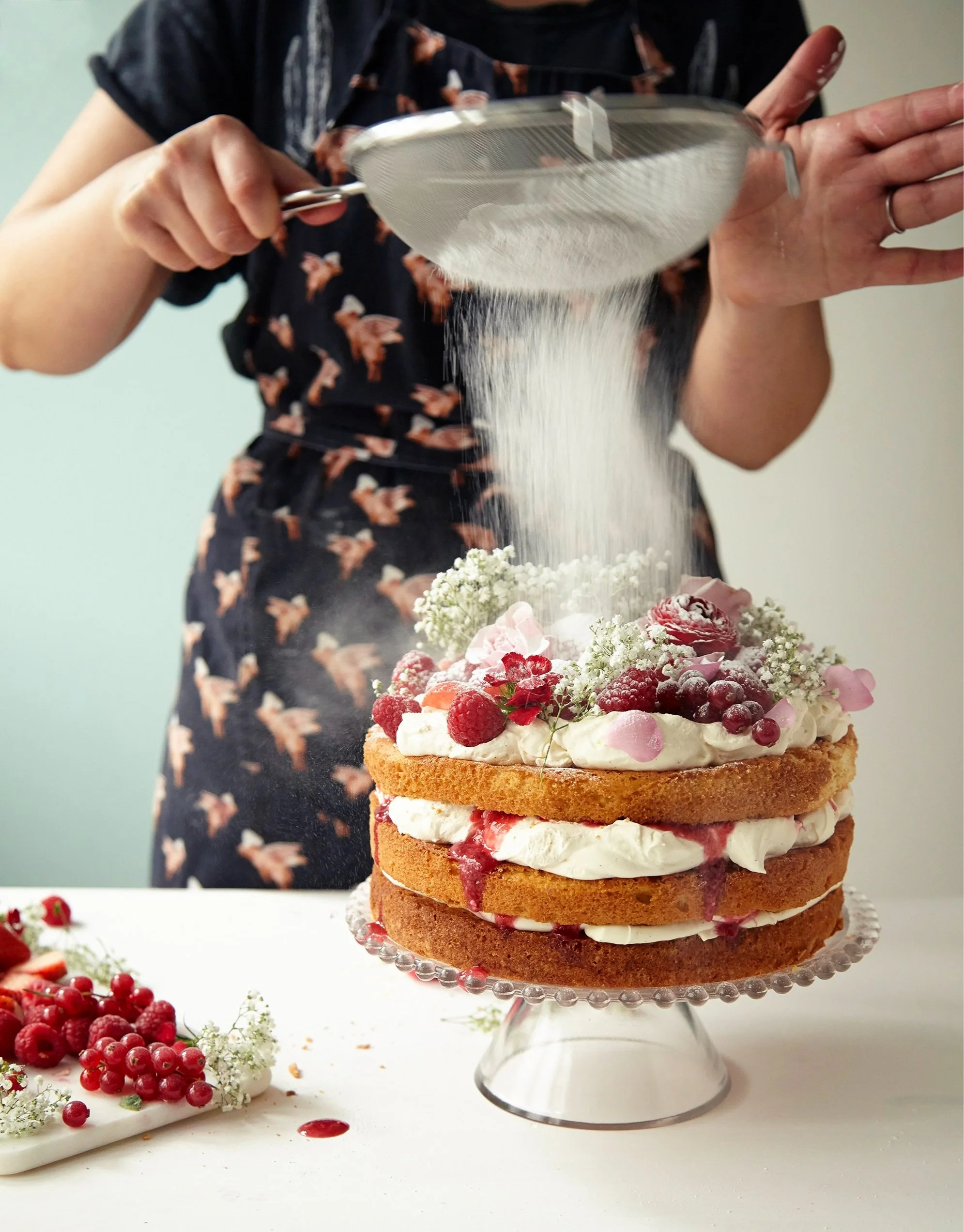 Sifting icing sugar onto summer berry cake