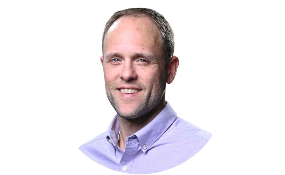 Headshot of a smiling man with short hair, wearing a light purple collared shirt.